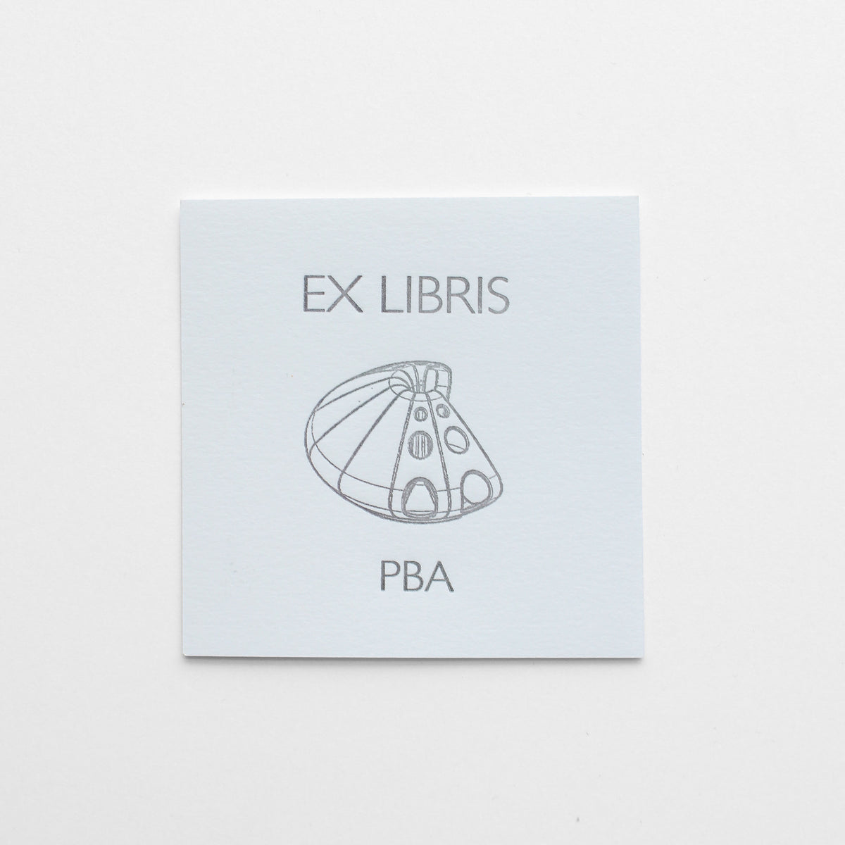 A square white card with the text 'Ex Libris PBA' and a simple gray line drawing in the center, printed in letterpress.